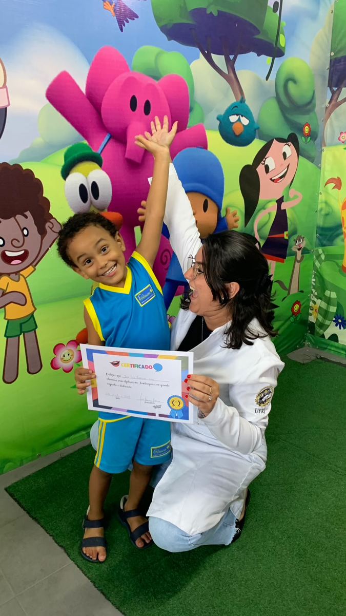 Criança comemorando o certificado de alta com a fonoaudióloga